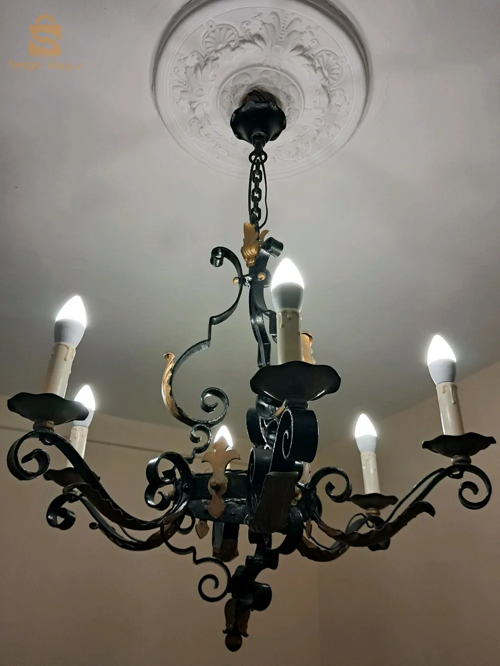 Gigantesque lustre, vintage, en fer forgé à six (06) bras de lumières, ornés de palettes dorées.