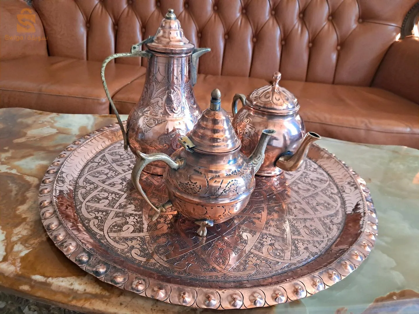 عرض بيع إبريقين للشاي وإبريق قهوة من النحاس. جميعها بأشكال وأحجام مختلفة، بمظهر حرفي ساحر وتقليدي.