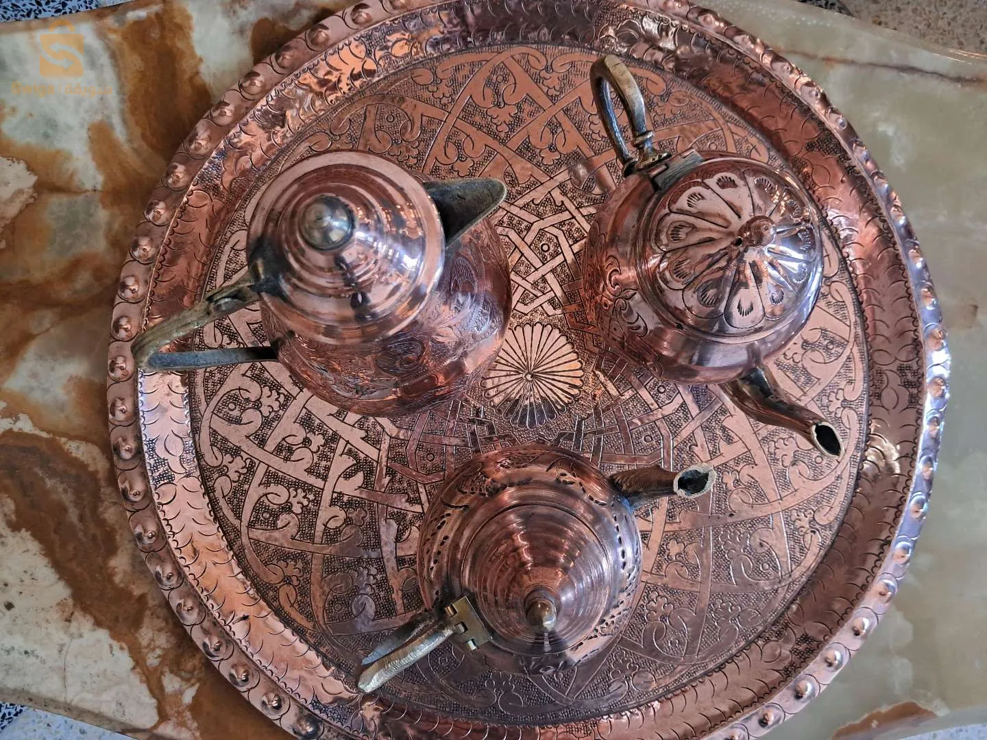 عرض بيع إبريقين للشاي وإبريق قهوة من النحاس. جميعها بأشكال وأحجام مختلفة، بمظهر حرفي ساحر وتقليدي.